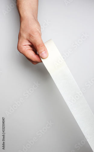 hand and Scotch tape on a gray background