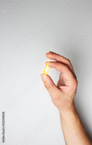 yellow capsule in hand on a light background