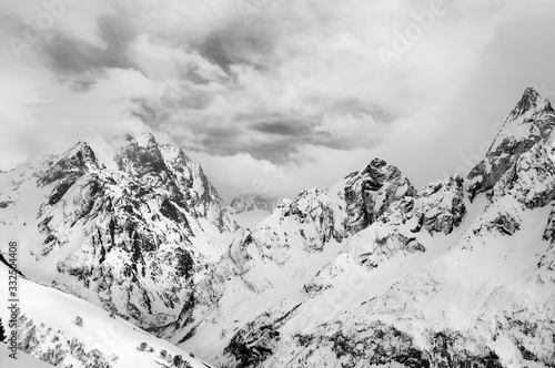 Gray high mountain peaks covered with ice and clouds at winter © BSANI