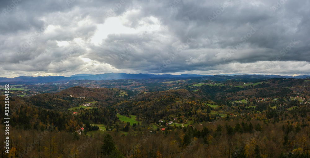 Panorama of notranjska region of slovenia in autumn colors, with dense clouds carrying storm approaching. Beautiful autumn weather viewed from Ulovka, visible mount Sneznik and Javornik.
