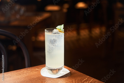 Vodka and tonic alcohol cocktail in highball glass decorated with ice and mint leaves on dark background photo