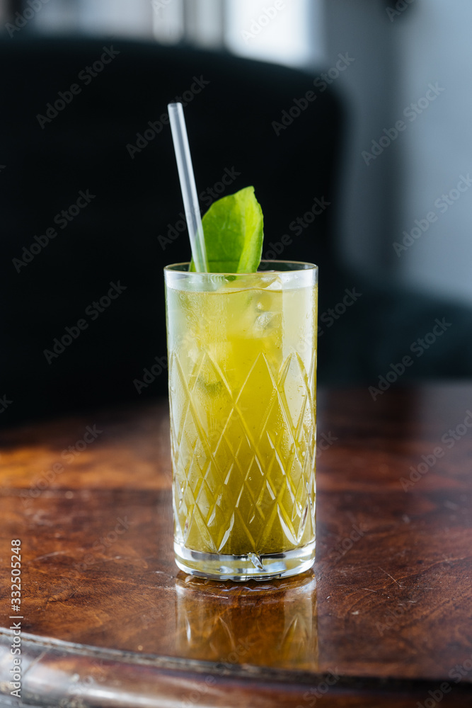 Tasty appetizing chilled lemonade with mint and straw on table in sunlight Tasty appetizing chilled lemonade with mint and straw on table in sunlight