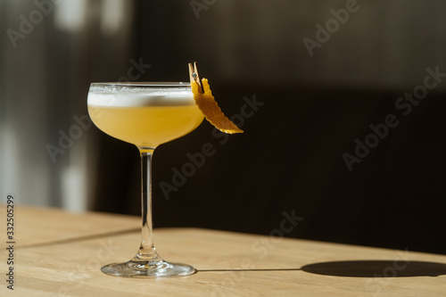 Close up of cocktail served in glass decorated with lemon peel