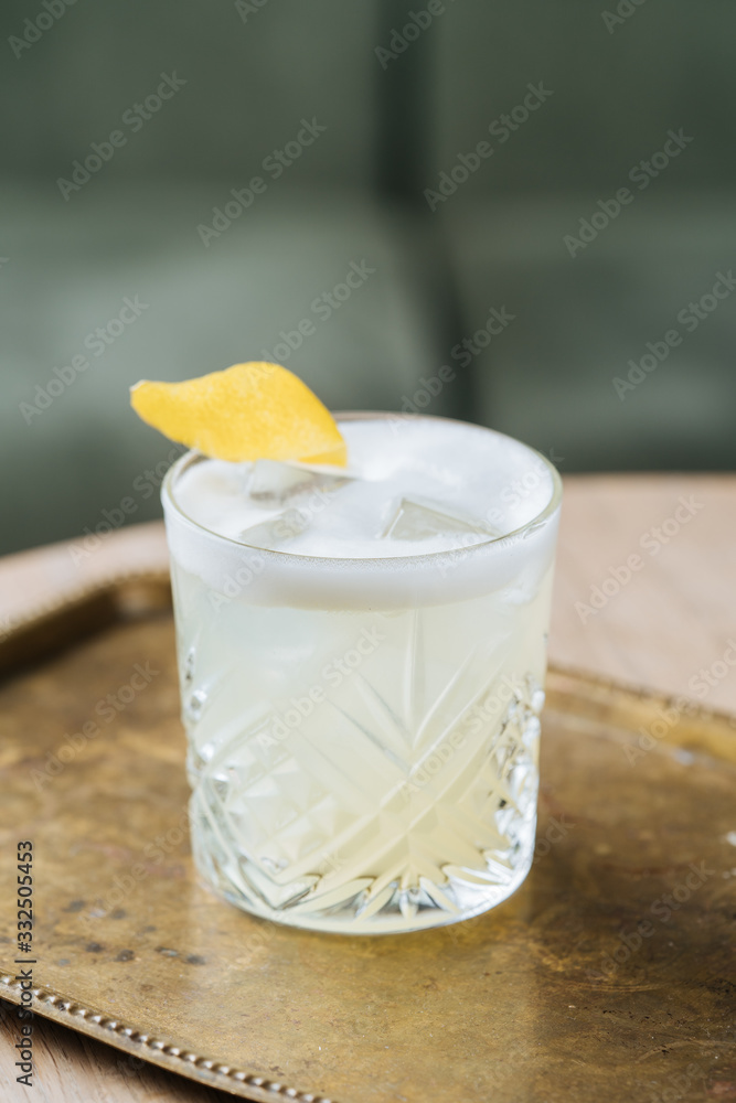 From above of alcohol cocktail with foam in stylish glass decorated with lemon zest on table neat sunglasses in restaurant From above of alcohol cocktail with foam in stylish glass decorated with lemon zest on table neat sunglasses in restaurant