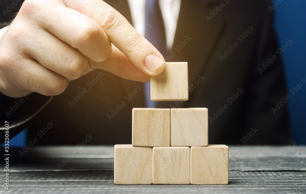 Businessman puts empty wooden blocks. Business management concept. Planning and strategy. Setting and achieving goals. Road map. Performance. Risk assessment. Investments Businessman puts empty wooden blocks. Business management concept. Planning and strategy. Setting and achieving goals. Road map. Performance. Risk assessment. Investments