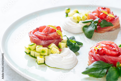 Salmon rolls with onion and herbs served on white ceramic plate on white table background photo