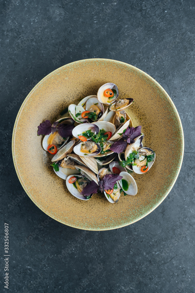 From above palatable mussels served with cut chili pepper and fresh basil leaves on plate in restaurant From above palatable mussels served with cut chili pepper and fresh basil leaves on plate in restaurant