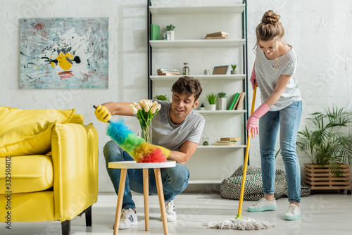 Fotografie happy man and woman doing spring cleaning in apartment