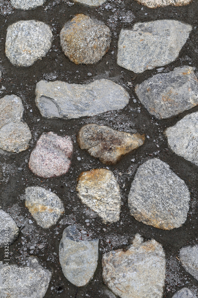 Road made of cobblestones and cement. Grey outdoor floor in a closeup from above. Sidewalk stones are asymmetrical and most of them have grey stones. Color image. Road made of cobblestones and cement. Grey outdoor floor in a closeup from above. Sidewalk stones are asymmetrical and most of them have grey stones. Color image.