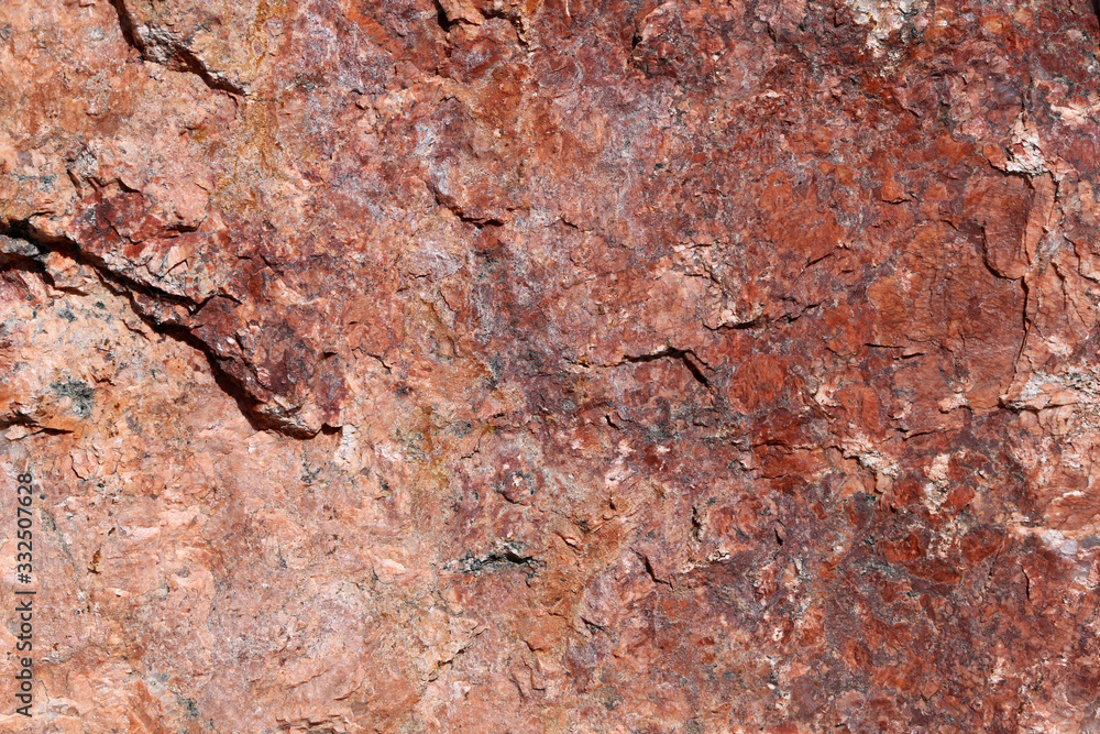 Closeup of a big solid stone in red, orange and black tones. In this photo you can see the rustic texture of the uneven surface of the rock in detail. Perfect grungy background image. Color photo. Closeup of a big solid stone in red, orange and black tones. In this photo you can see the rustic texture of the uneven surface of the rock in detail. Perfect grungy background image. Color photo.