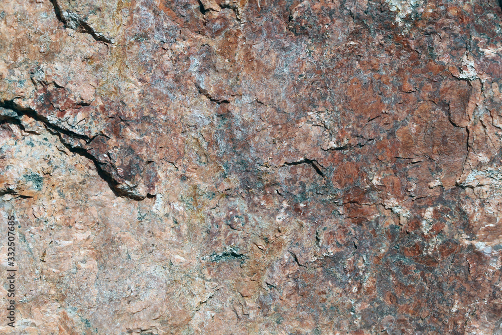 Closeup of a big solid stone in red, orange and black tones. In this photo you can see the rustic texture of the uneven surface of the rock in detail. Perfect grungy background image. Color photo. Closeup of a big solid stone in red, orange and black tones. In this photo you can see the rustic texture of the uneven surface of the rock in detail. Perfect grungy background image. Color photo.