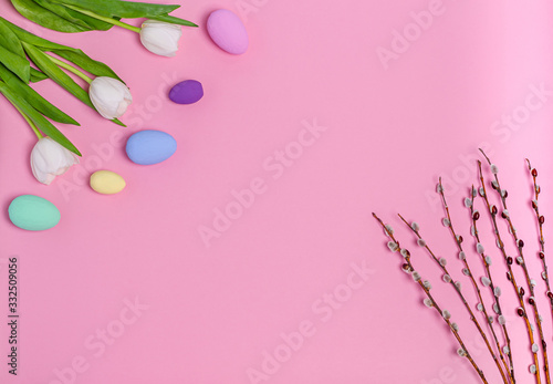 Easter colored eggs, a bouquet of white tulips and pussy-willow branches on a pink background, copy space