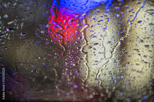 Abstract colorful background of glass surface with water drops and blurred city lights.
