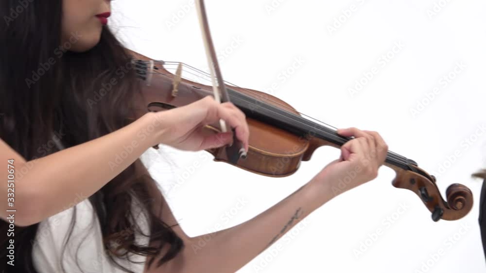 Asian girl playing the violin with group female on a white background. Close up. Steadicam shot Asian girl playing the violin with group female on a white background. Close up. Steadicam shot