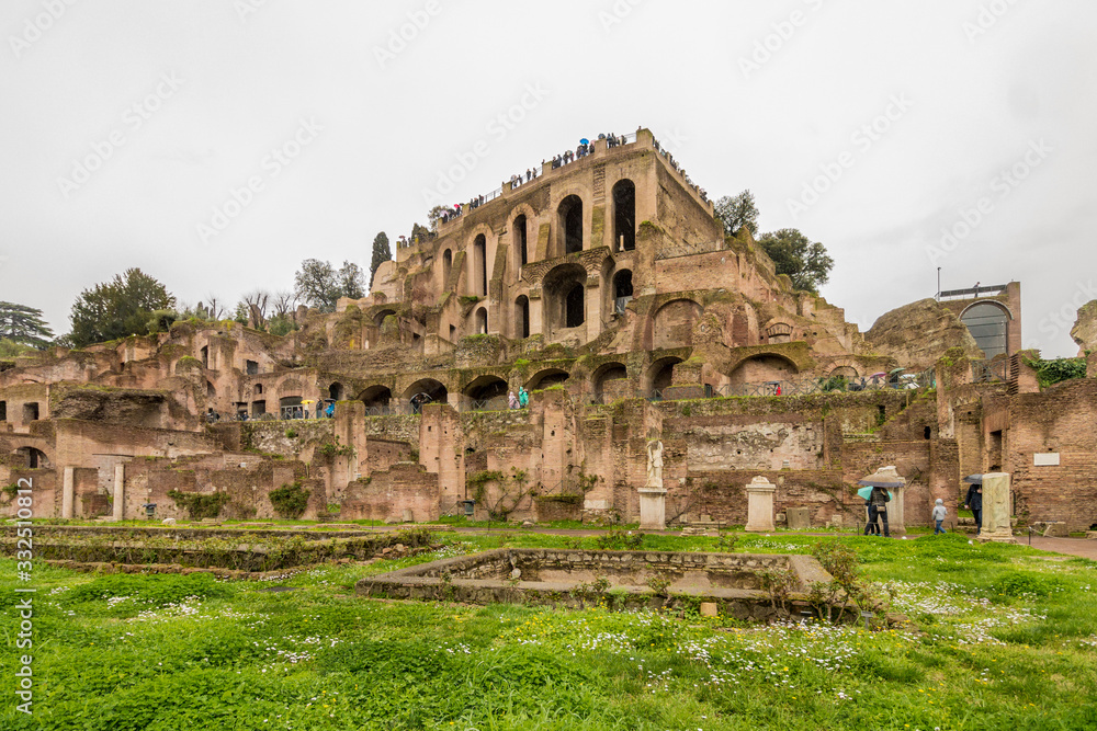 Ruins view of the Roman Forum in Rome, Italy on a cloudy autumn day with green grass.