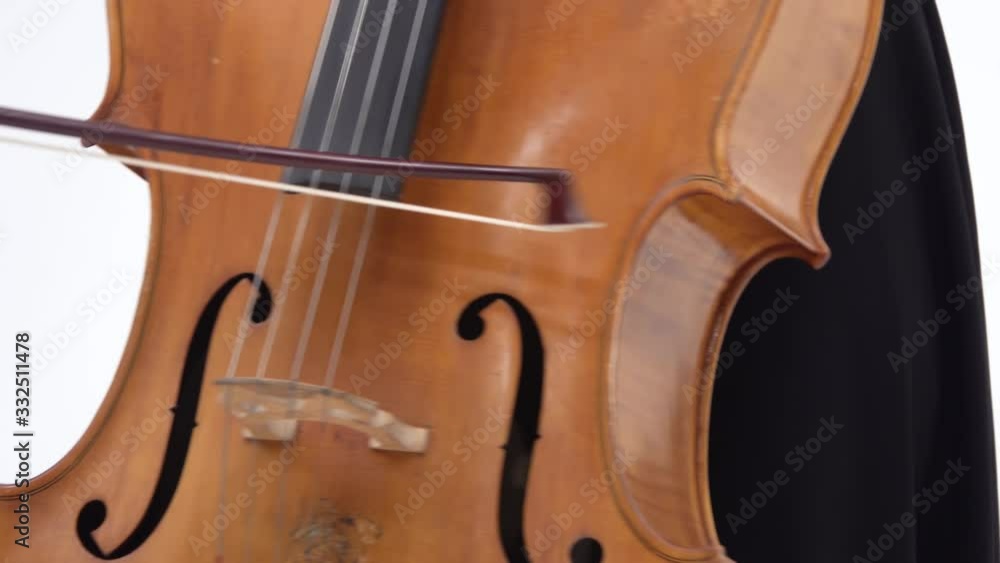 Brunette woman is playing the cello on white background. Right female hand with ring on finger. Close up. Steadicam shot Brunette woman is playing the cello on white background. Right female hand with ring on finger. Close up. Steadicam shot