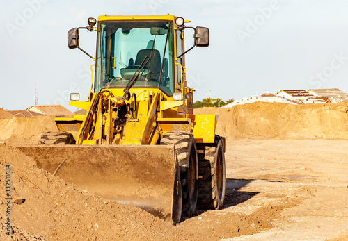 A front end loader with several piles of fresh dirt