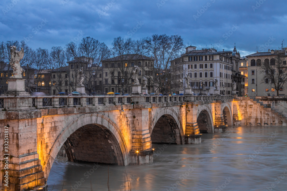 Tiber river bridge on a cloudy autumn sunset with light set. Long exposure in Rome, Italy. Top view.