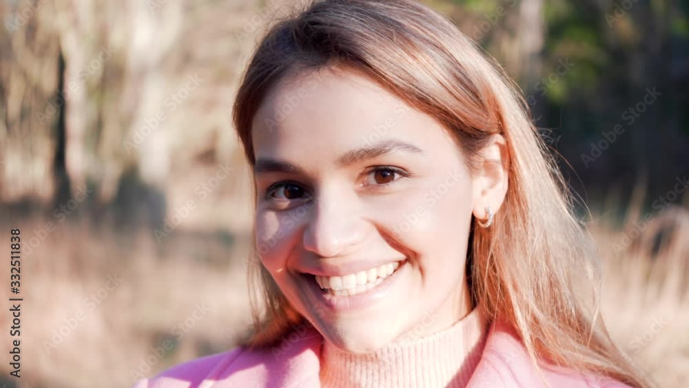 Beautiful young woman looking into camera smiling. Handsome stylish girl laughing. Outdoors in the nature portrait shot. 