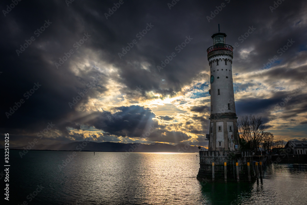 Lighthouse in port of Lindau town by the bodensee lake in Germany with dark clouds and Alp mountains in the background
