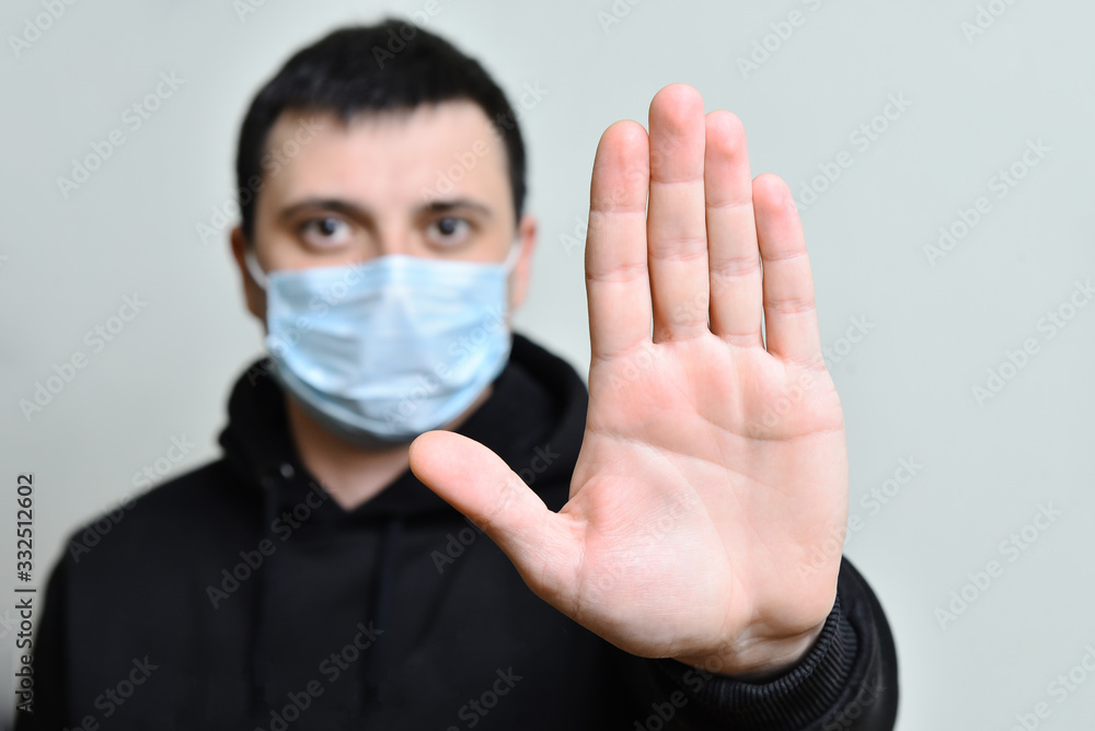 Man in protective medical mask on his face show stop viruse by hand gesture. Man in protective medical mask on his face show stop viruse by hand gesture.