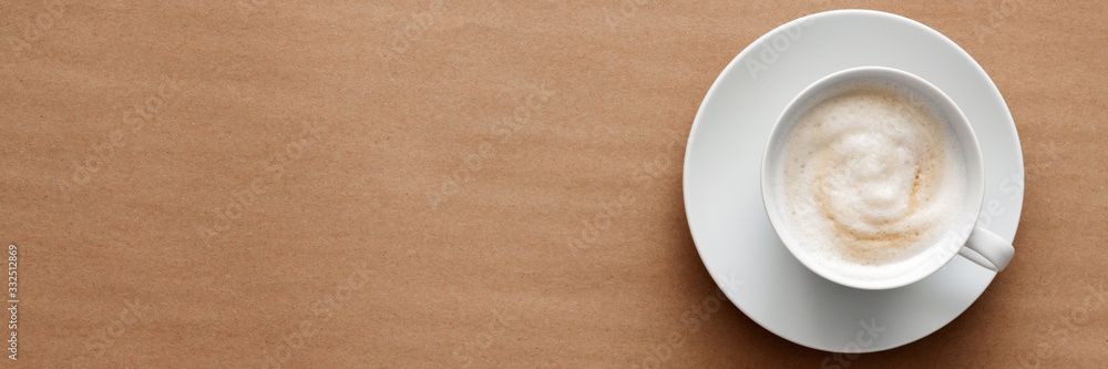 Cappuccino coffee on a brown empty background. View from above. Copy space with space for text. Coffee foam. Morning at work. Panorama Cappuccino coffee on a brown empty background. View from above. Copy space with space for text. Coffee foam. Morning at work. Panorama