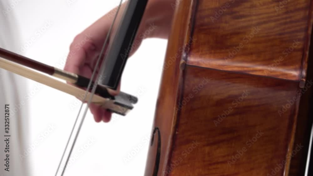 Woman is playing the cello on white background. Close up of bow and strings. Steadicam shot Woman is playing the cello on white background. Close up of bow and strings. Steadicam shot