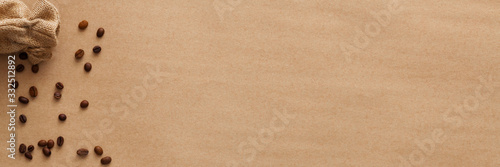 Coffee on a brown empty background. View from above. Copy space with space for text. Scattered coffee beans and jute bag. Panorama