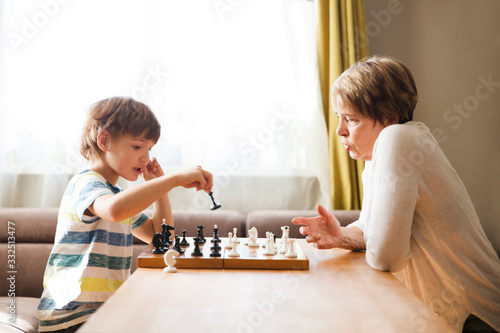 grandmom with grandson play chess together at home. quarantine. health concept. Corona Virus. Quality Time. Family having fun playing at home. stay home concept