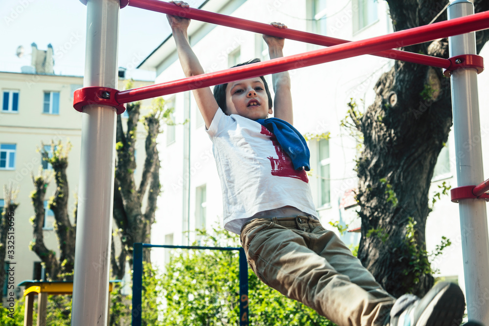Fototapeta premium little cute blond boy hanging on playground outside, alone training with fun, lifestyle children concept
