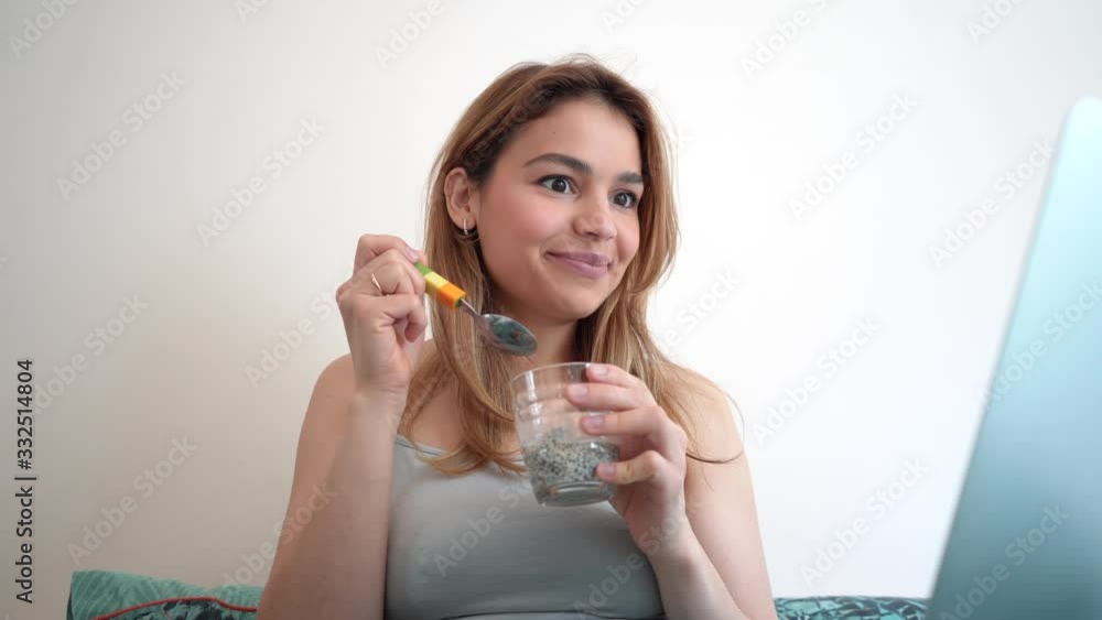 Beautiful funny young woman eating healthy while using laptop device in bed. Cute girl influencer in bed. Modern lifestyle. Beautiful funny young woman eating healthy while using laptop device in bed. Cute girl influencer in bed. Modern lifestyle.