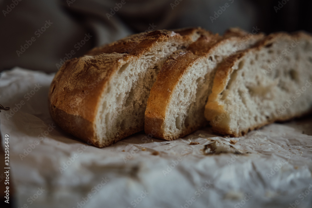 Flat-lay of freshly baked sourdough bread loaf and bread slices on rustic wooden board over grey concrete table Flat-lay of freshly baked sourdough bread loaf and bread slices on rustic wooden board over grey concrete table