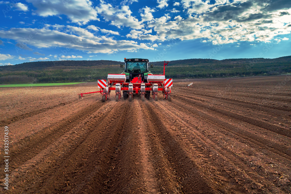 Fototapeta premium Farmer with tractor seeding crops at field