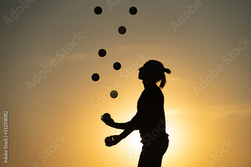 Silhouette of juggler with balls on colorful sunset