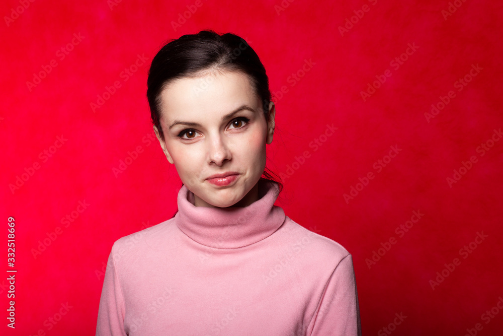 beautiful girl in a pink turtleneck talking on the phone on a red background beautiful girl in a pink turtleneck talking on the phone on a red background