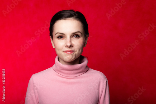 beautiful girl in a pink turtleneck talking on the phone on a red background © Диана Шиловская