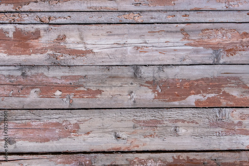 old wooden fence made of planks with peeling red paint with cracks and crevices. rough surface texture