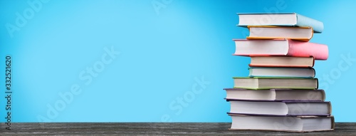 Stack of colorful school books on wooden desk