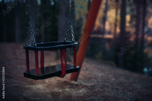 Empty single swing at playground outside, dramatic end of days