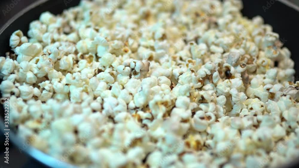 Close-up of fresh yellow popcorn in cooking pan at home, preparation salty or sweet popcorn for watching film, entertainment with food. Cinema popcorn Close-up of fresh yellow popcorn in cooking pan at home, preparation salty or sweet popcorn for watching film, entertainment with food. Cinema popcorn