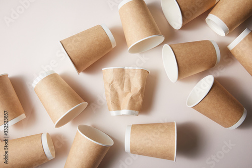 Slika na platnu paper cups with rumpled cup in middle isolated on brown background