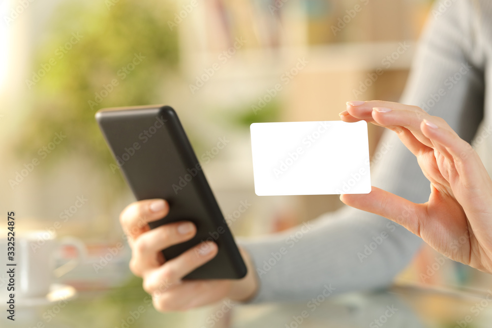 Woman hands with phone showing blank credit card