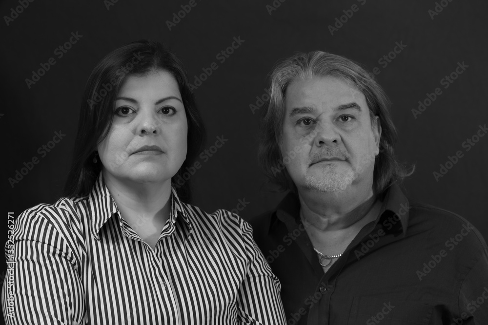 Couple Studio portrait in black and white. They are posing and looking to the camera. Couple Studio portrait in black and white. They are posing and looking to the camera.