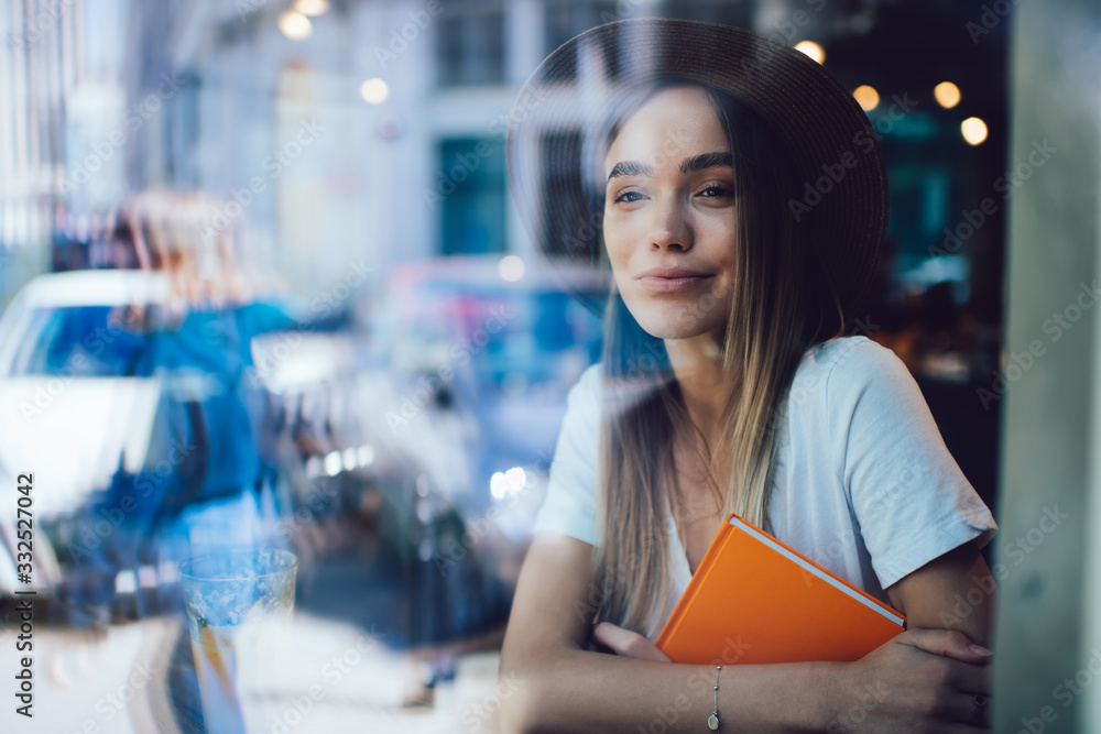 Fototapeta premium Female student with orange book resting in cafe