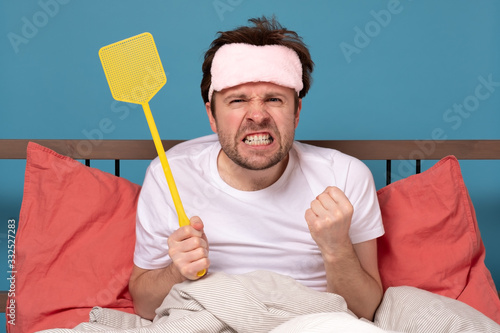 man holding a fly swatter wanting to kill annoying mosquito