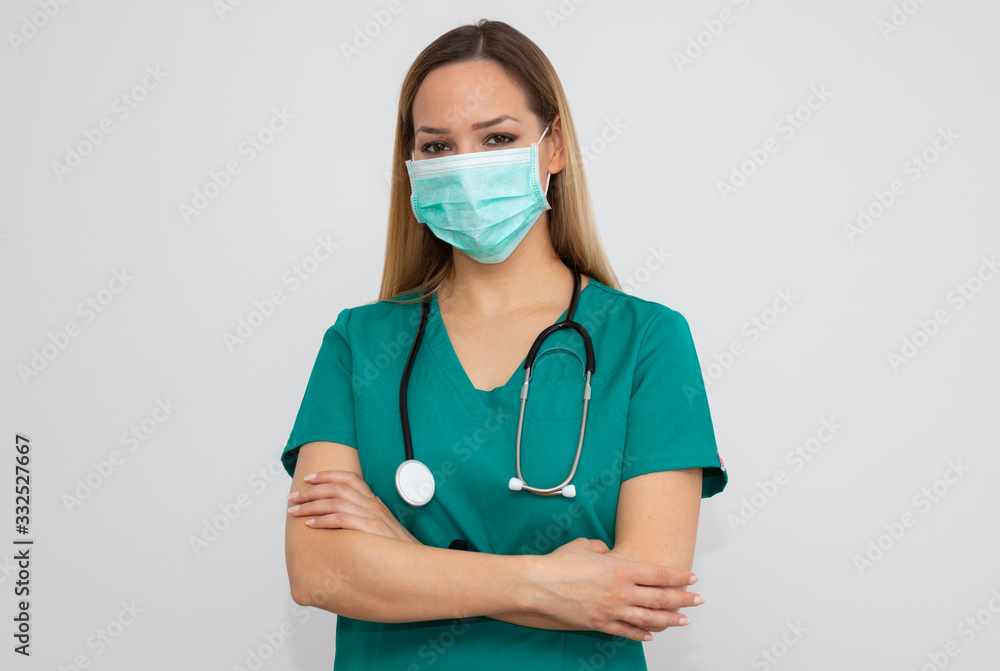 Female nurse standing arms crossed. Confident young woman doctor. Female nurse young pretty woman in green clothes with medical mask posing. Female nurse standing arms crossed. Confident young woman doctor. Female nurse young pretty woman in green clothes with medical mask posing.