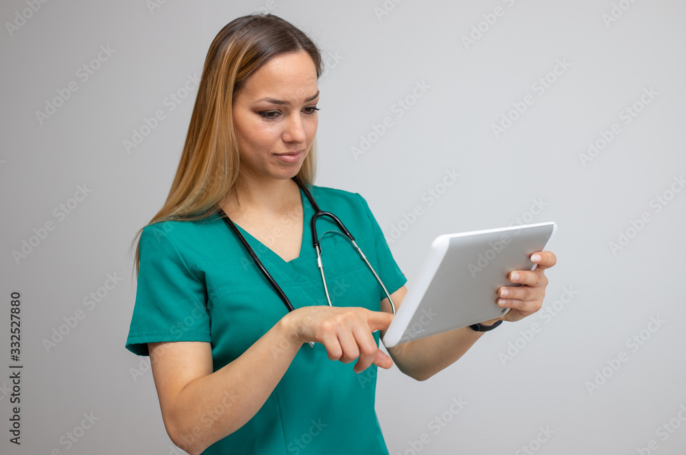 Smiling young nurse pointing at tablet isolated on white Smiling young nurse pointing at tablet isolated on white