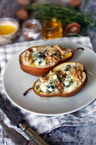 Baked pears with blue cheese, nuts and honey on a plate. French cuisine. Keto diet. Vegetarian lunch.