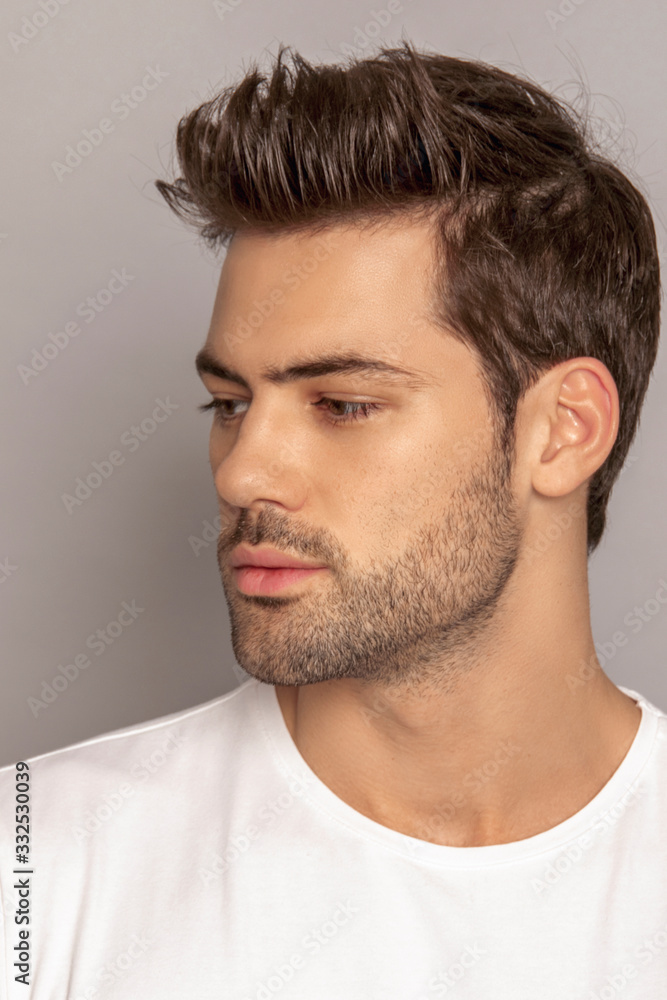 Obraz premium Muscle strong face beautiful stripped male model portrait in denim blue jeans white t-shirt on grey isolated font background with shadow