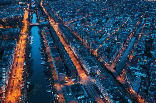 Beautiful night aerial view of Amsterdam downtown from above with many narrow canals, illuminated streets and old historic houses, drone photo Fototapet